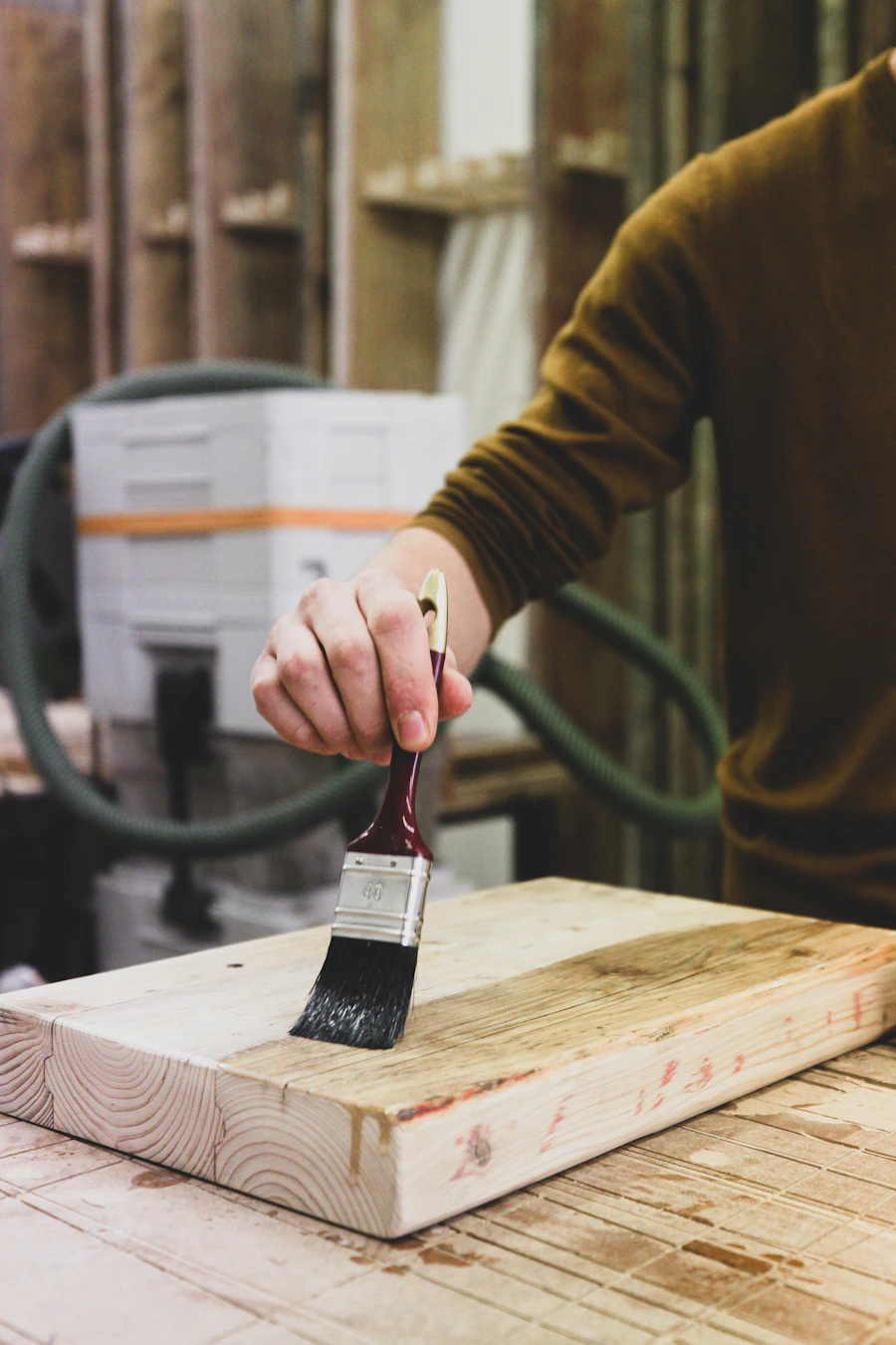 A finisher brushing a coat onto a wood panel in a workshop