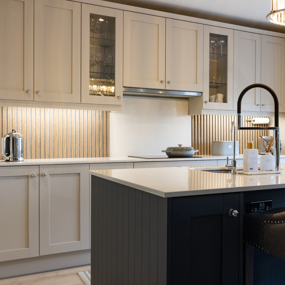 Painted cream shaker cabinets with glass-front uppers and a navy kitchen island